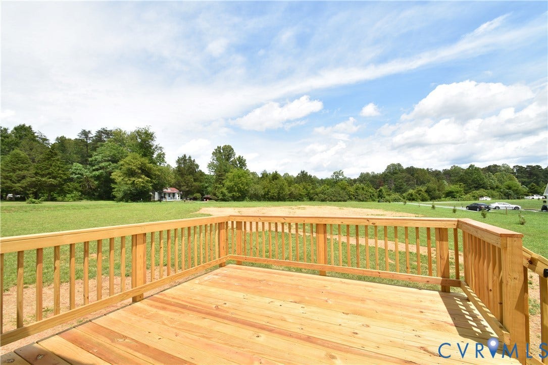 Spacious wood-finish deck overlooking an expansive grassy area with mature trees