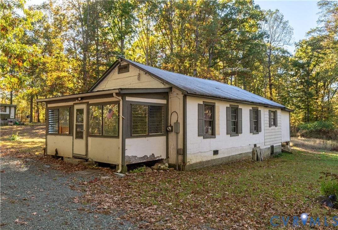 View of side of property featuring a sunroom, view of wooded area, and concrete block siding