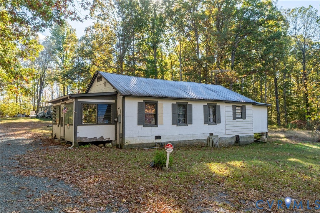 View of side of home featuring a metal roof, crawl space, and view of wooded area