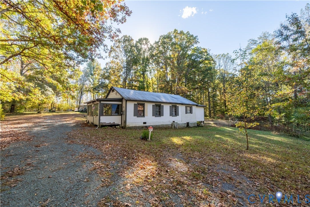 Bungalow featuring gravel driveway, a sunroom, a front yard, and a metal roof