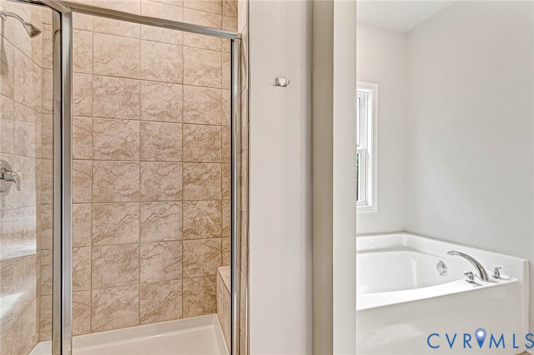 Shower enclosure with glass door, tiled walls, and a built-in bench