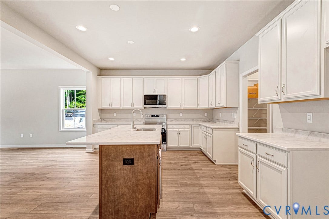 Kitchen featuring white cabinetry with silver hardware, light-toned countertops, and wood-finish flooring