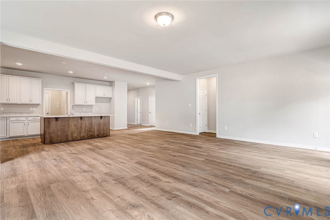 Spacious open-concept living area featuring wood-finish flooring, recessed lighting, and a neutral color palette