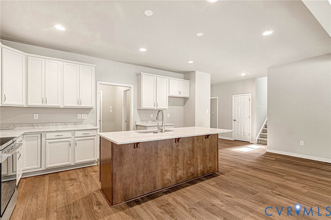 Spacious kitchen featuring a central island with a wood-finish base, ample white cabinetry, and light-toned countertops