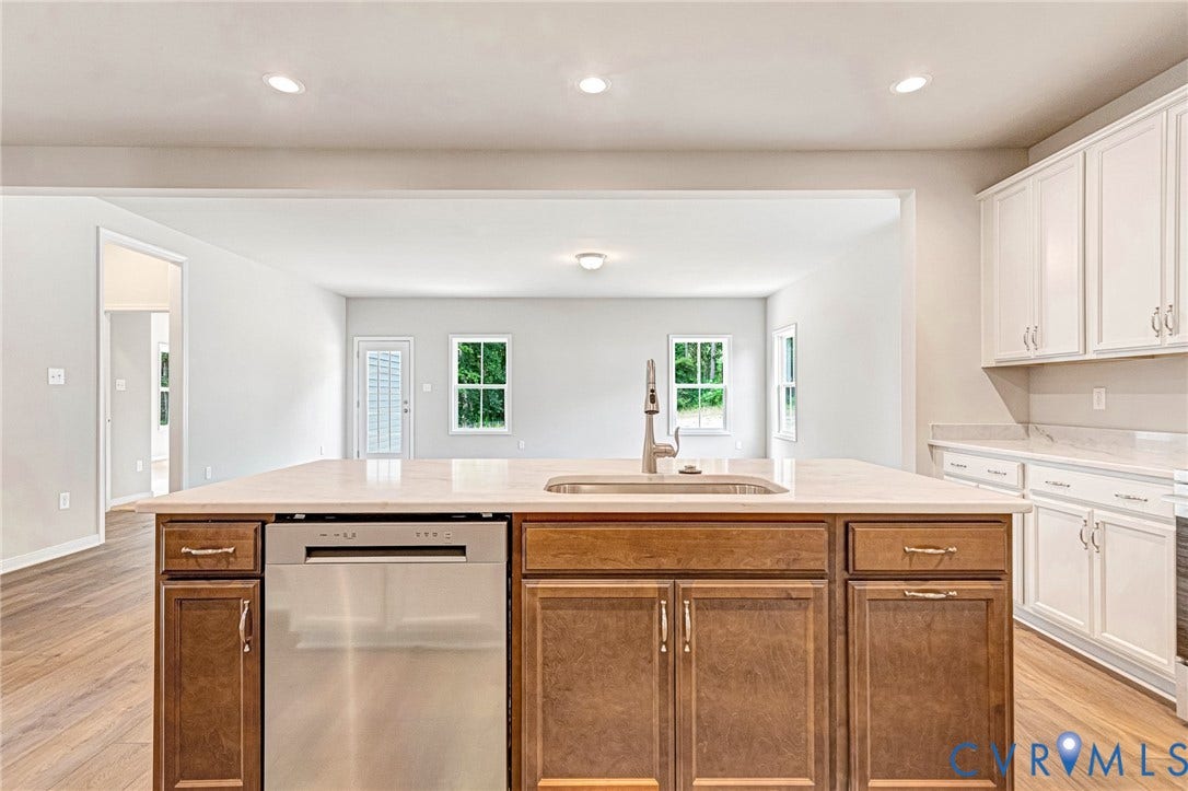 Kitchen island featuring a stainless steel sink with a modern faucet, integrated dishwasher, and rich wood-finish cabinetry