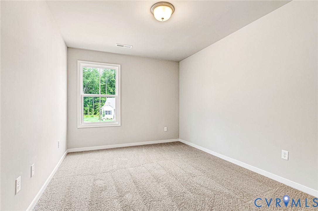 Neutral-toned room featuring a single window, light-colored walls, and textured carpeting