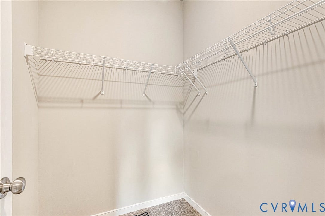 Closet with white wire shelving, light neutral wall paint, and gray carpet flooring