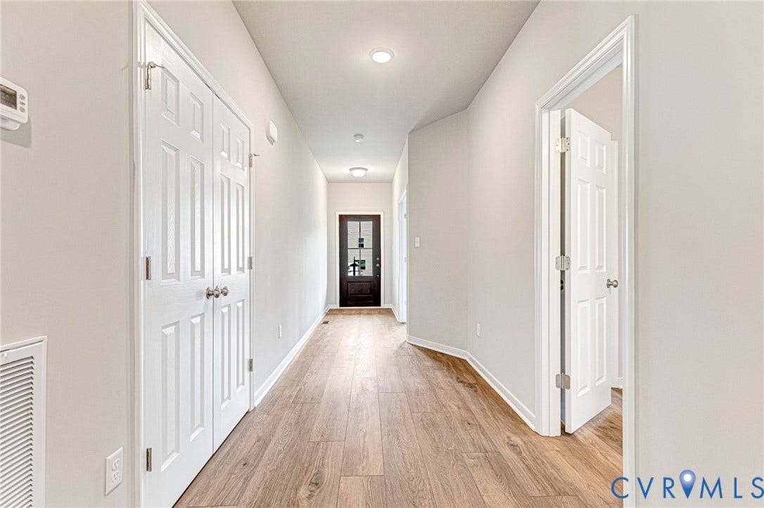Hallway featuring wood-finish flooring, recessed lighting, neutral wall tones, white trim, and a paneled entry door with frosted glass