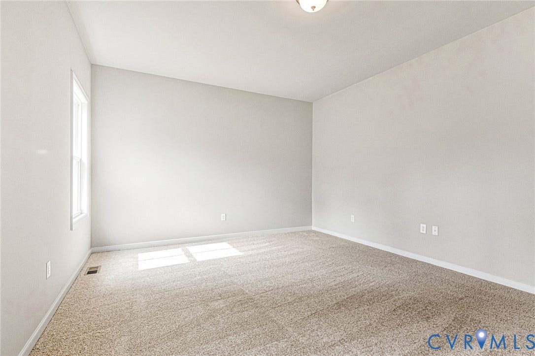 Spacious room featuring neutral carpeting and light-toned walls, a single window, and a ceiling-mounted light fixture
