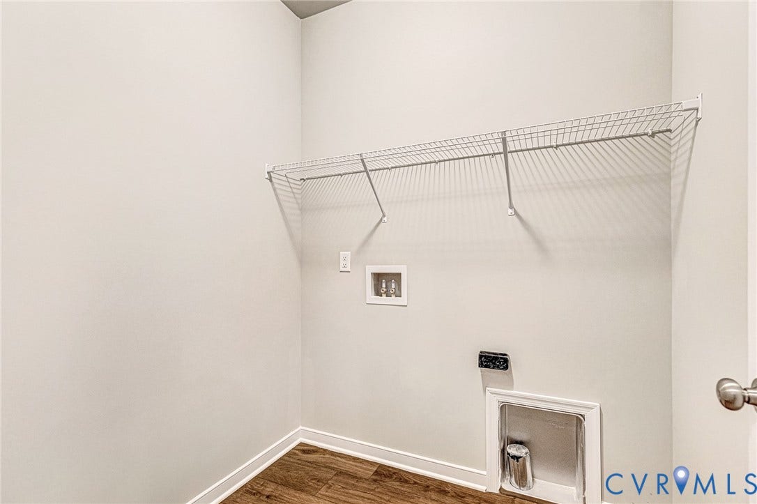 Dedicated laundry space featuring a wire shelving unit, appliance hookups, and wood-finish flooring