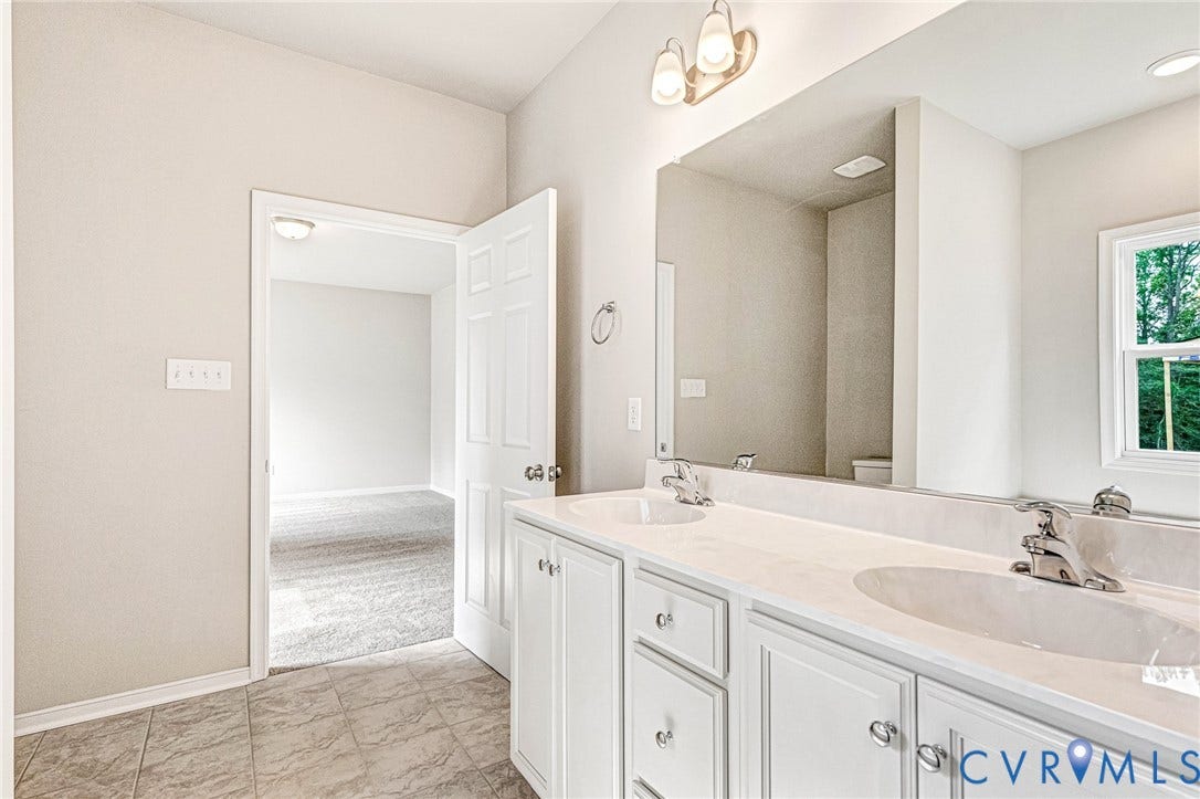 Bathroom featuring a double vanity with white cabinetry, light-toned countertops, and dual undermount sinks