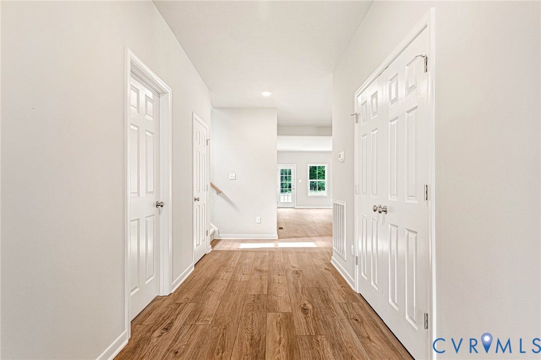 Entryway featuring wood-finish flooring, white paneled doors, recessed lighting, and a staircase with a light wood handrail
