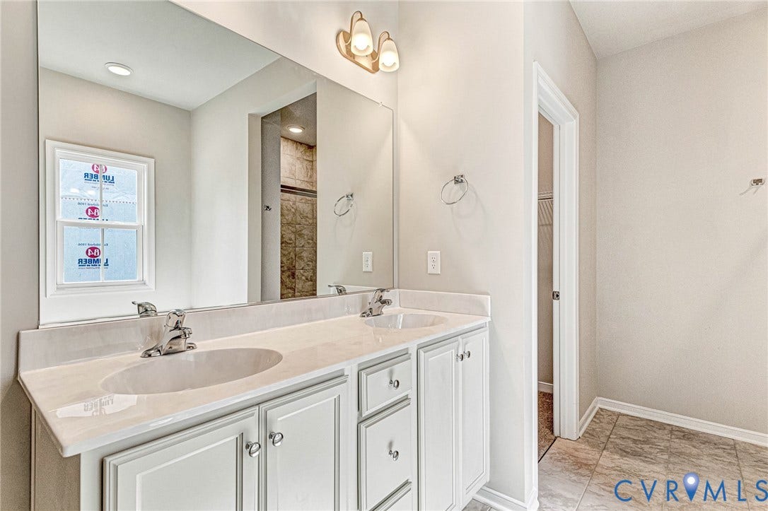Double vanity with undermount sinks and chrome fixtures, illuminated by an overhead light fixture