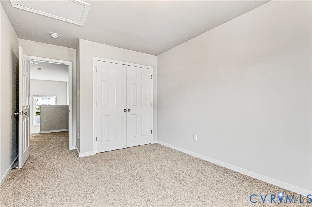 Carpeted room featuring a double-door closet with panel detailing, white baseboards, and neutral wall paint