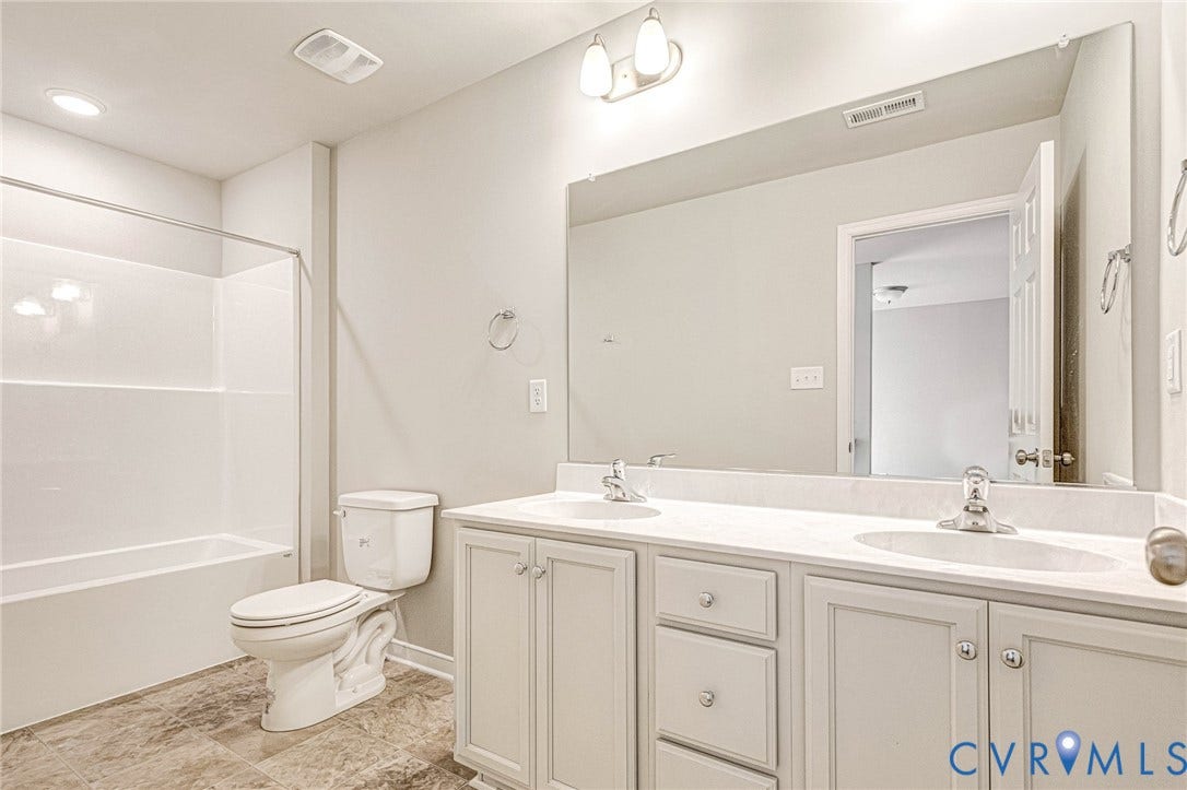 Bathroom featuring a double vanity with white cabinetry, light-toned countertops, and dual integrated sinks