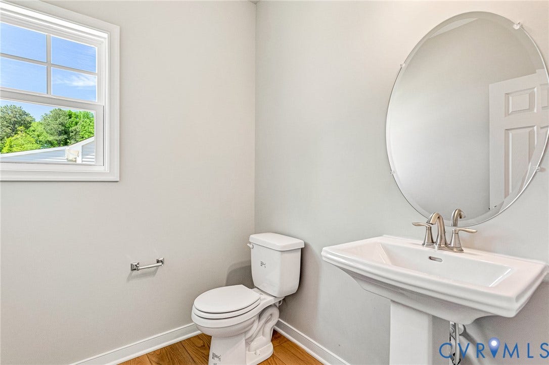 12606 Poplar Village Place, Poplar Village, Chester, VA 23831 Pedestal sink with brushed nickel faucet, oval mirror, and wood-finish flooring