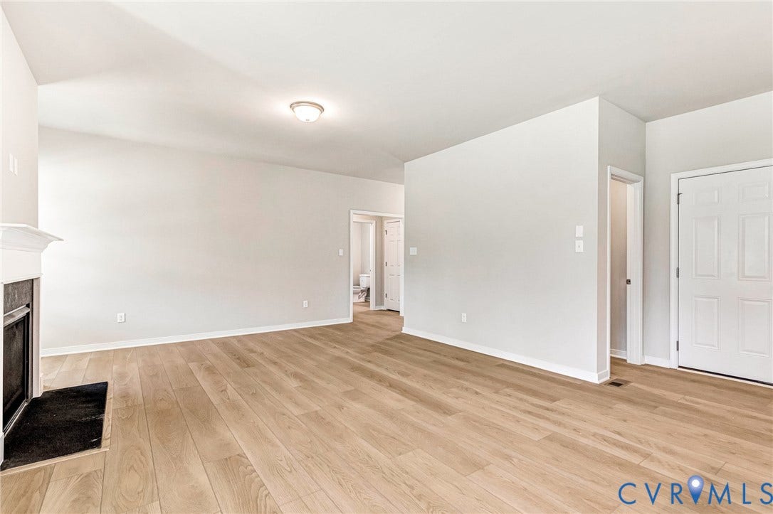 12606 Poplar Village Place, Poplar Village, Chester, VA 23831 Spacious interior featuring wood-finish flooring, light gray wall paint, and a fireplace with a white mantel and dark hearth
