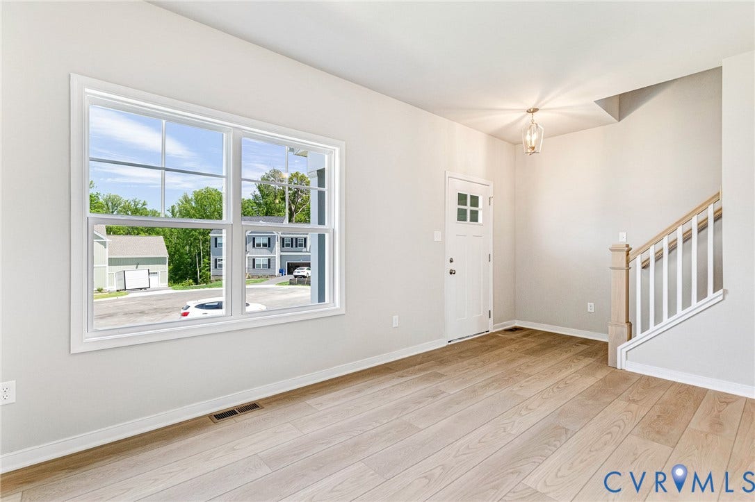 12606 Poplar Village Place, Poplar Village, Chester, VA 23831 Bright interior featuring a large multi-pane window, wood-finish flooring, white baseboards, a classic white entry door with glass inserts, and a staircase with white balusters