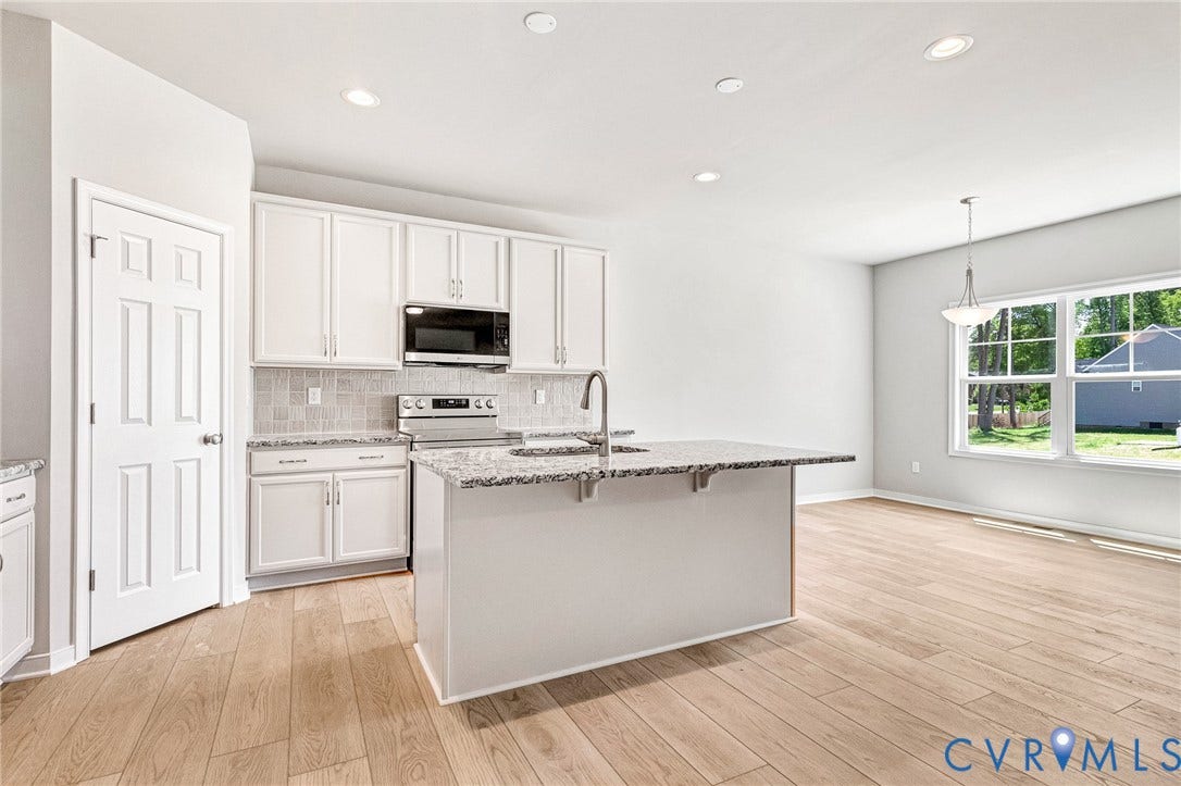 12606 Poplar Village Place, Poplar Village, Chester, VA 23831 Spacious kitchen featuring an island with sink, white shaker cabinetry, stainless steel appliances, speckled countertops, and a tiled backsplash