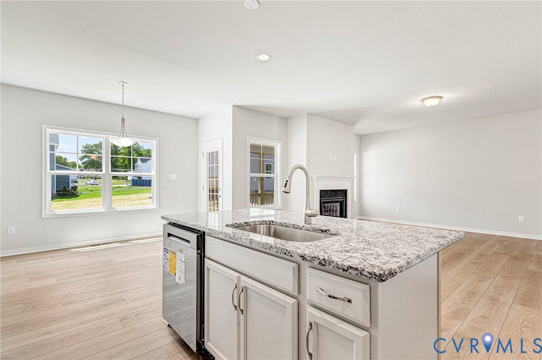 12606 Poplar Village Place, Poplar Village, Chester, VA 23831 Kitchen island featuring a stainless steel sink, gooseneck faucet, light granite countertop, and white cabinetry