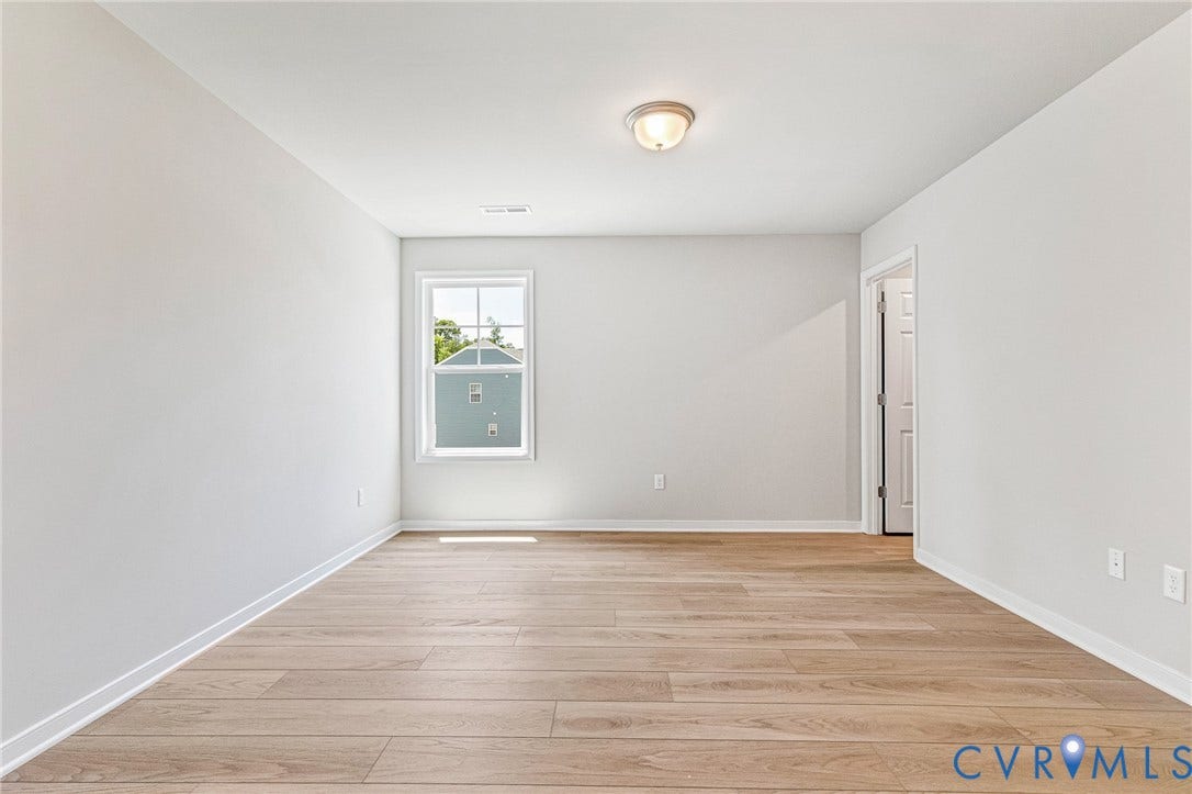 12606 Poplar Village Place, Poplar Village, Chester, VA 23831 Spacious interior room featuring light wood-finish flooring, white baseboards, and a single window with white trim