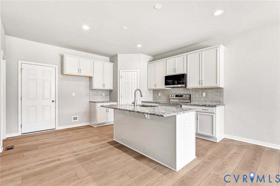 12606 Poplar Village Place, Poplar Village, Chester, VA 23831 Modern kitchen featuring a central island, white shaker-style cabinetry, granite countertops, stainless steel appliances, and wood-finish flooring