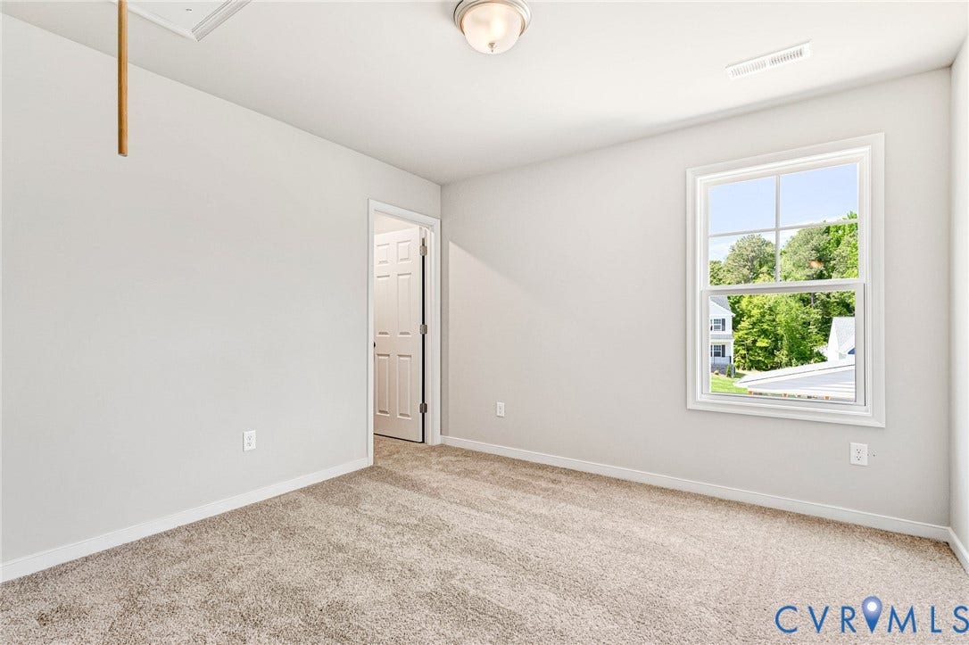 12606 Poplar Village Place, Poplar Village, Chester, VA 23831 Carpeted interior space featuring light neutral wall paint, white trim, a double-hung window with exterior greenery, and a flush mount ceiling light
