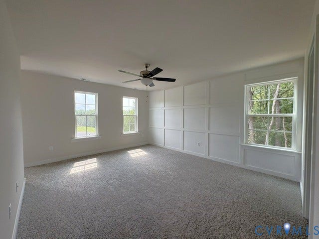 162 Bacon Bit Ln, Louisa, VA 23093 Bright and spacious primary living area featuring multiple windows with natural light, neutral carpeting throughout, ceiling fan, and built-in wall cabinetry with clean white finishes