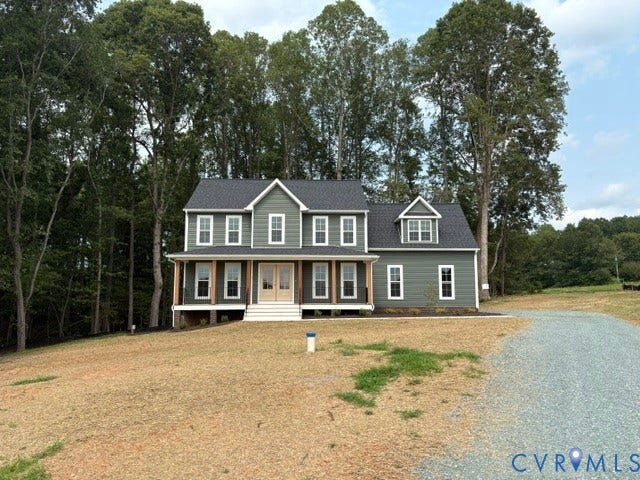 162 Bacon Bit Ln, Louisa, VA 23093 Two-story residence with a covered porch, dormer window, gravel driveway, and surrounding mature trees