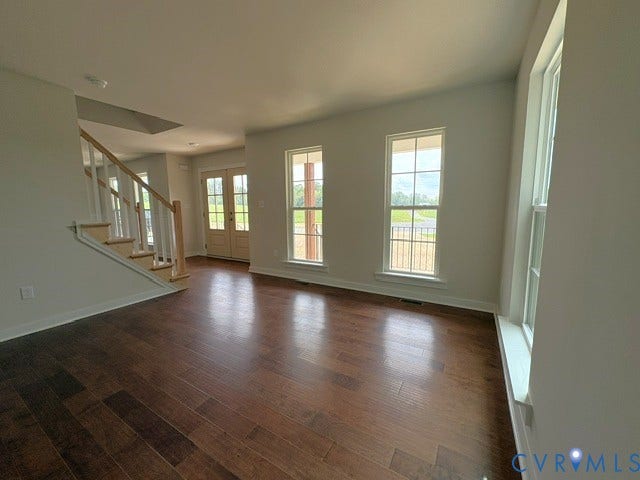 162 Bacon Bit Ln, Louisa, VA 23093 Hardwood flooring, painted white walls, white trim throughout, white staircase with wood handrail, and multiple windows