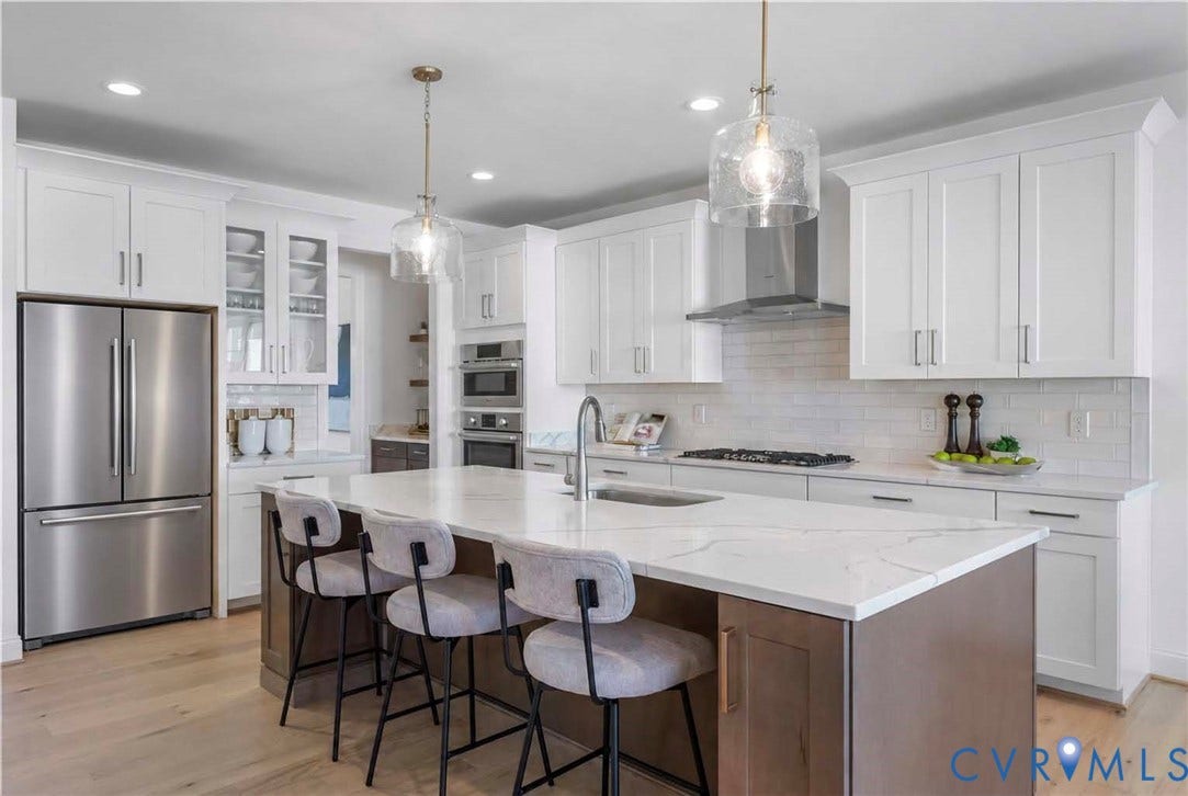Kitchen featuring white shaker cabinetry, stainless steel appliances, a center island with countertop seating, a subway tile backsplash, and light wood-finish flooring