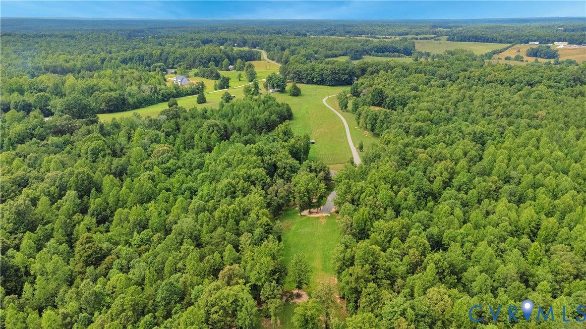 4337 Riddles Bridge Road, Riddles Bridge, Goochland, VA 23063 Expansive wooded acreage featuring a cleared building site, a paved driveway, and a pond