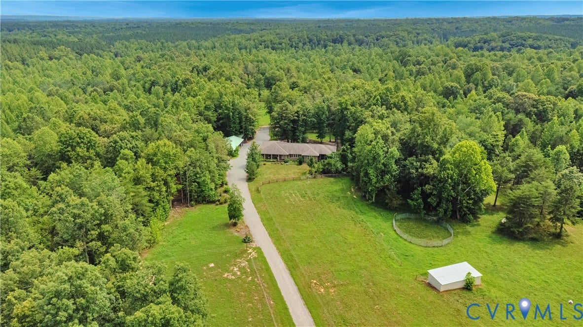 4337 Riddles Bridge Road, Riddles Bridge, Goochland, VA 23063 Expansive property featuring a residence, gravel driveway, open green fields, a metal outbuilding, and mature tree coverage