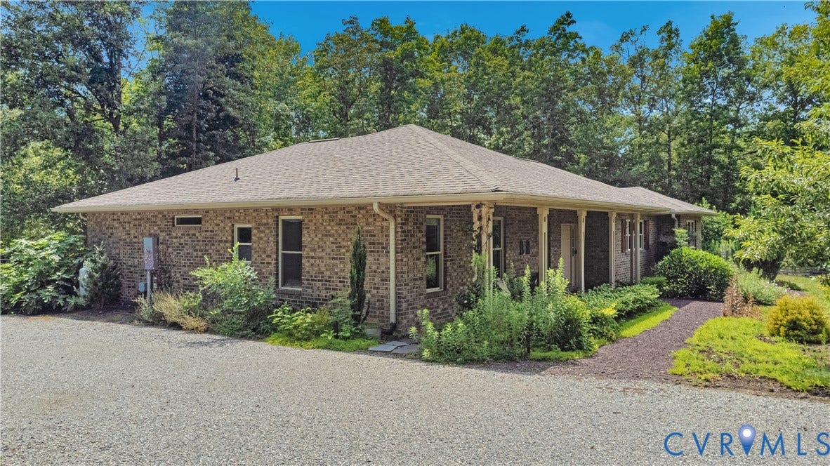 4337 Riddles Bridge Road, Riddles Bridge, Goochland, VA 23063 Ranch-style exterior with brick siding, a light-toned shingled roof, a covered porch with white pillars, and a landscaped entry path