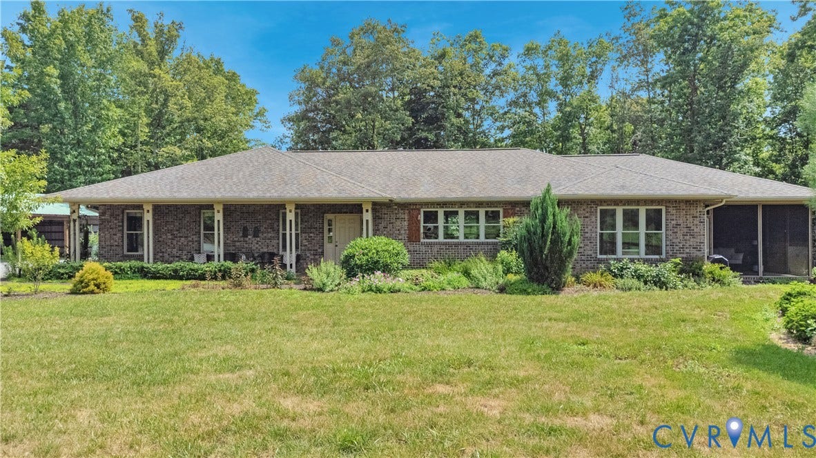 4337 Riddles Bridge Road, Riddles Bridge, Goochland, VA 23063 Brick ranch-style residence featuring a covered front porch with white columns, a screened-in porch, a shingled roof, and a mature treeline backdrop