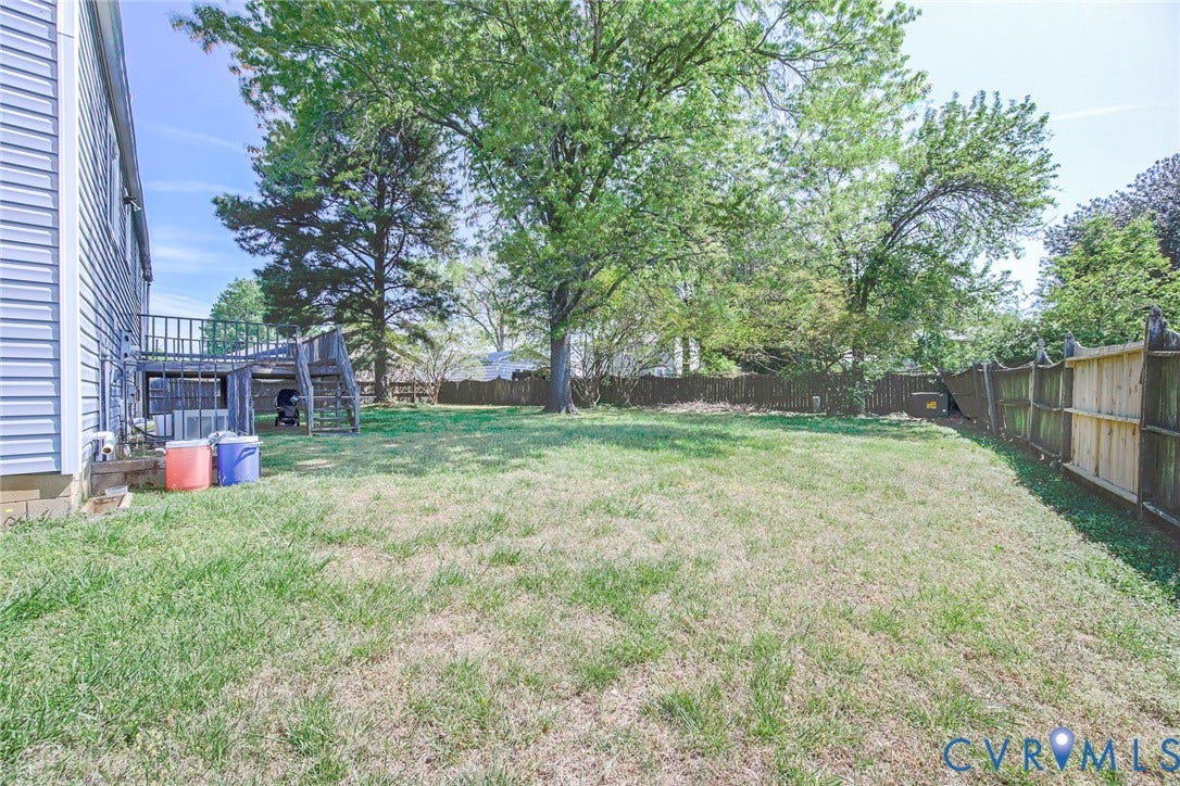 Expansive grassy yard with mature trees and partial fencing
