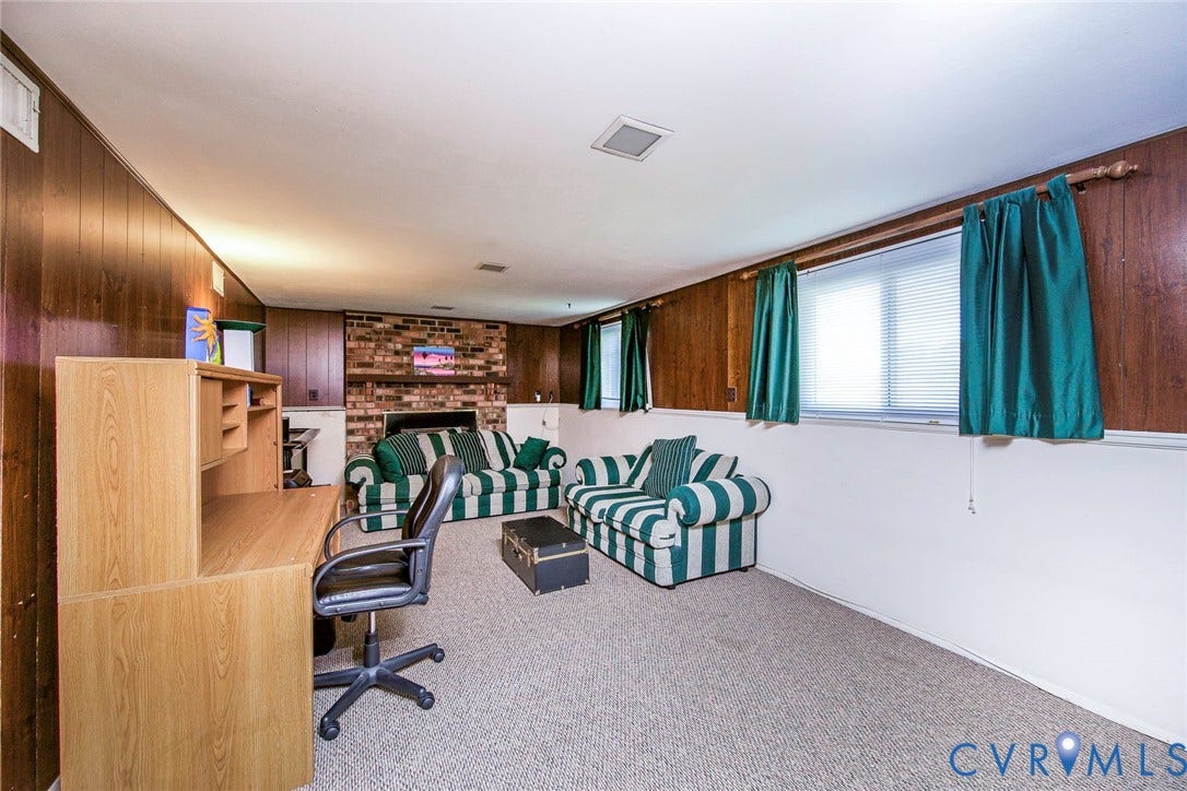 The property features a spacious room with wood paneling, a brick fireplace, and three windows