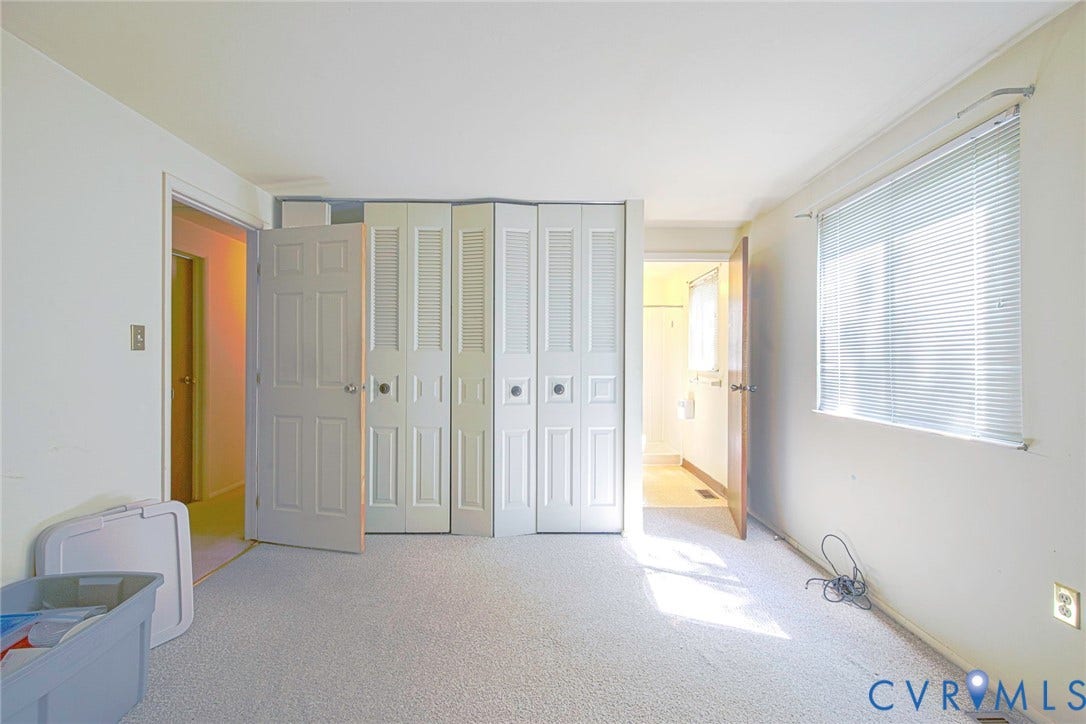 Carpeted interior space with a window featuring horizontal blinds