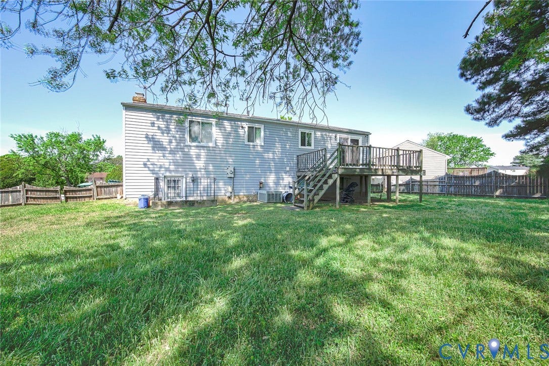 The property features a spacious backyard with a well-maintained lawn and a wooden privacy fence