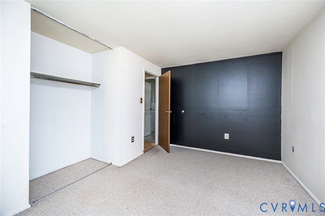 Room featuring light-colored carpet flooring, white walls, and a contrasting dark accent wall