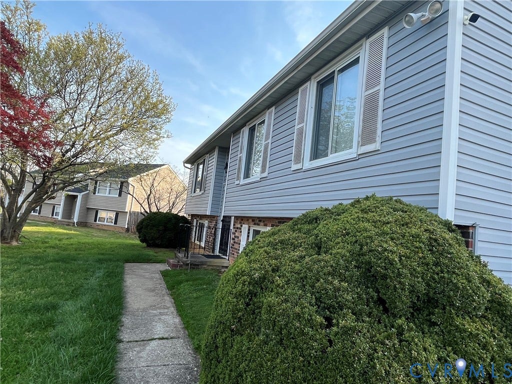 View of side of home featuring brick siding and a lawn
