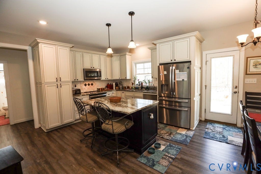 5670 Hickory Street, Powhatan, VA 23139 Two tone kitchen featuring stainless steel appliances, a kitchen bar, light stone countertops, a center island, and dark wood-style flooring