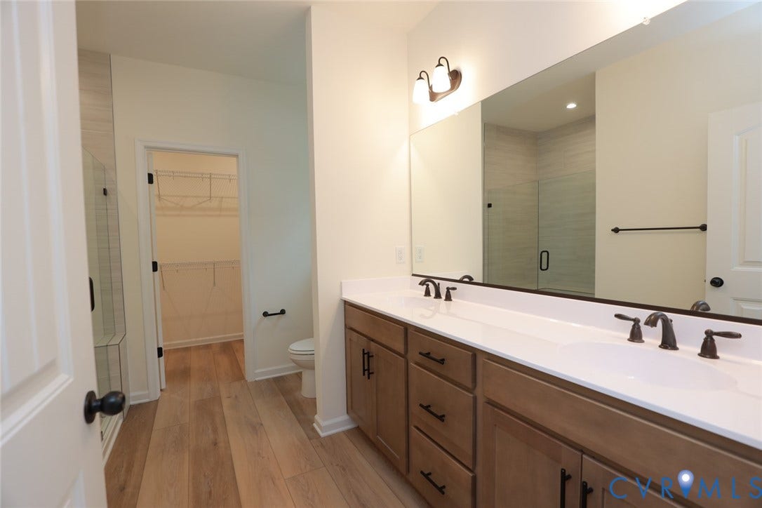 6305 Lila Crest Lane, Cottages At Millwood, Chesterfield, VA 23112 The photo represents the plan, not the actual home. Design selections may vary. The first-floor primary suite offers a spacious walk-in closet and an ensuite bath with a double vanity, soaking tub, and linen closet.