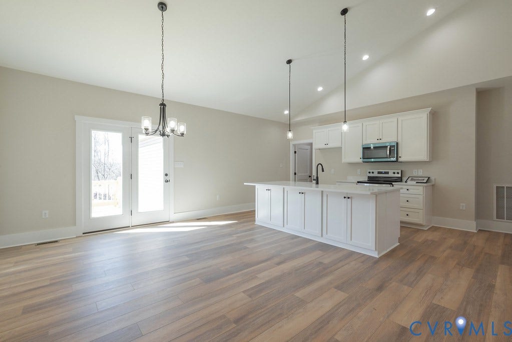 TBD Black Haw Lane, Hanover, VA 23059 Kitchen featuring vaulted ceiling, white cabinets, hanging lights, stainless steel microwave, and a kitchen island with sink