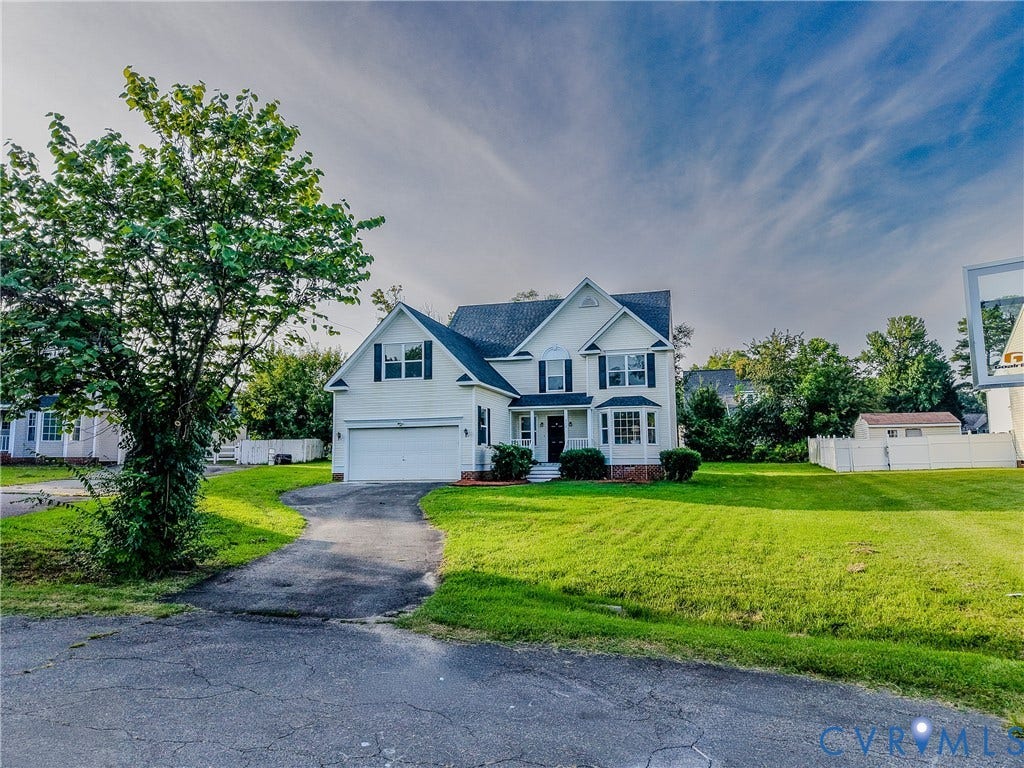 912 Harmony Road, Fairfield, VA 23059 Classic Colonial-style residence showcasing a clean asphalt driveway, two-car garage with white paneling, and a meticulously manicured lawn anchored by mature shade trees