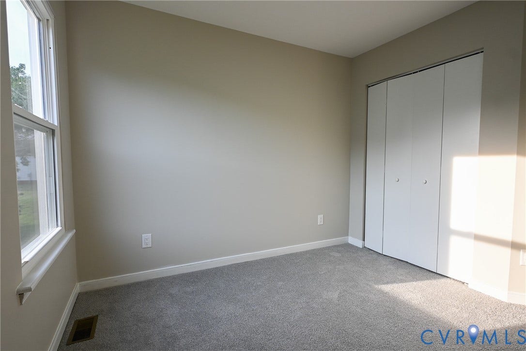 912 Harmony Road, Fairfield, VA 23059 Bright, light-filled bedroom with large windows, neutral wall finishes, carpeted flooring, and a spacious closet with bifold doors
