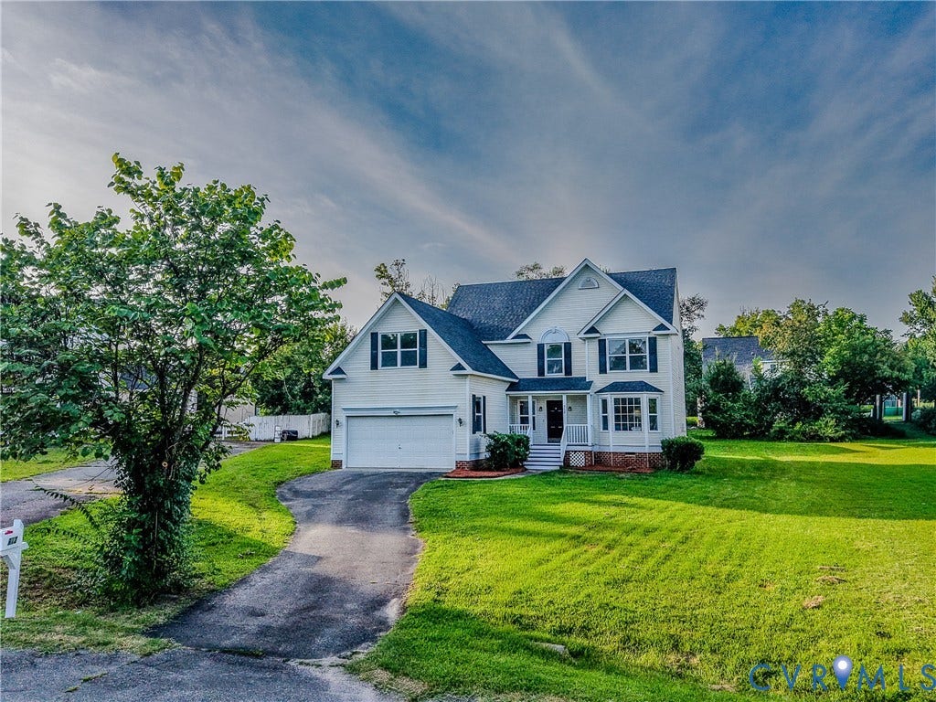 912 Harmony Road, Fairfield, VA 23059 White siding with dark shutters, front porch, attached garage, paved driveway, and expansive front lawn