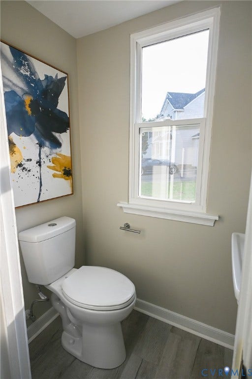 912 Harmony Road, Fairfield, VA 23059 Bright powder room featuring a two-piece toilet with elongated bowl, ceramic tile flooring, neutral wall finishes, and a large double-hung window with white trim providing natural light and outdoor views