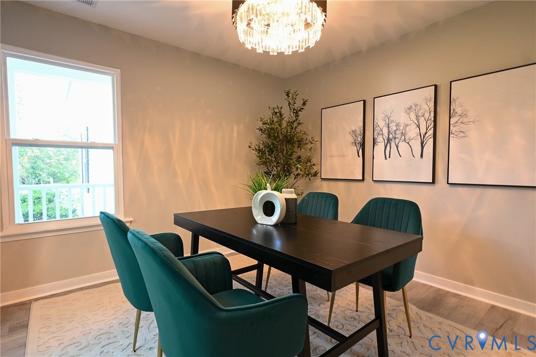 912 Harmony Road, Fairfield, VA 23059 Sophisticated dining space featuring a black wood-finish table, teal upholstered chairs with metal frames, neutral wall finishes, large picture windows with natural light, decorative botanical artwork, and a crystal chandelier fixture overhead