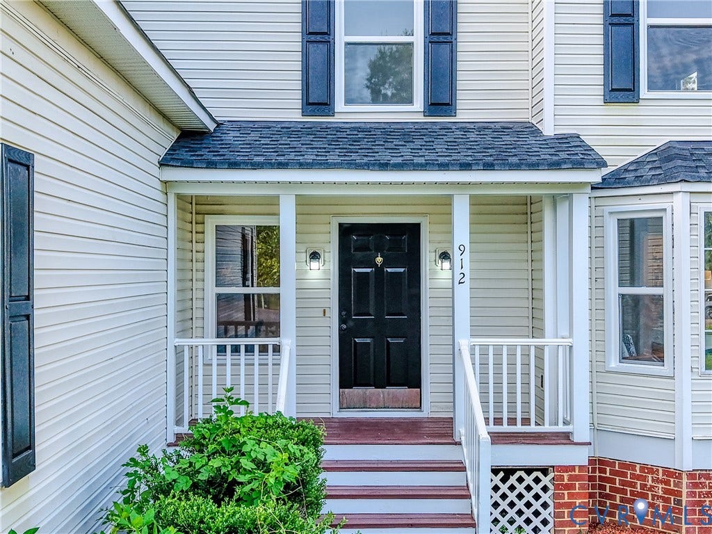 912 Harmony Road, Fairfield, VA 23059 Welcoming front entry featuring a black six-panel door, white column supports, brick foundation detailing, and a covered porch with white railings